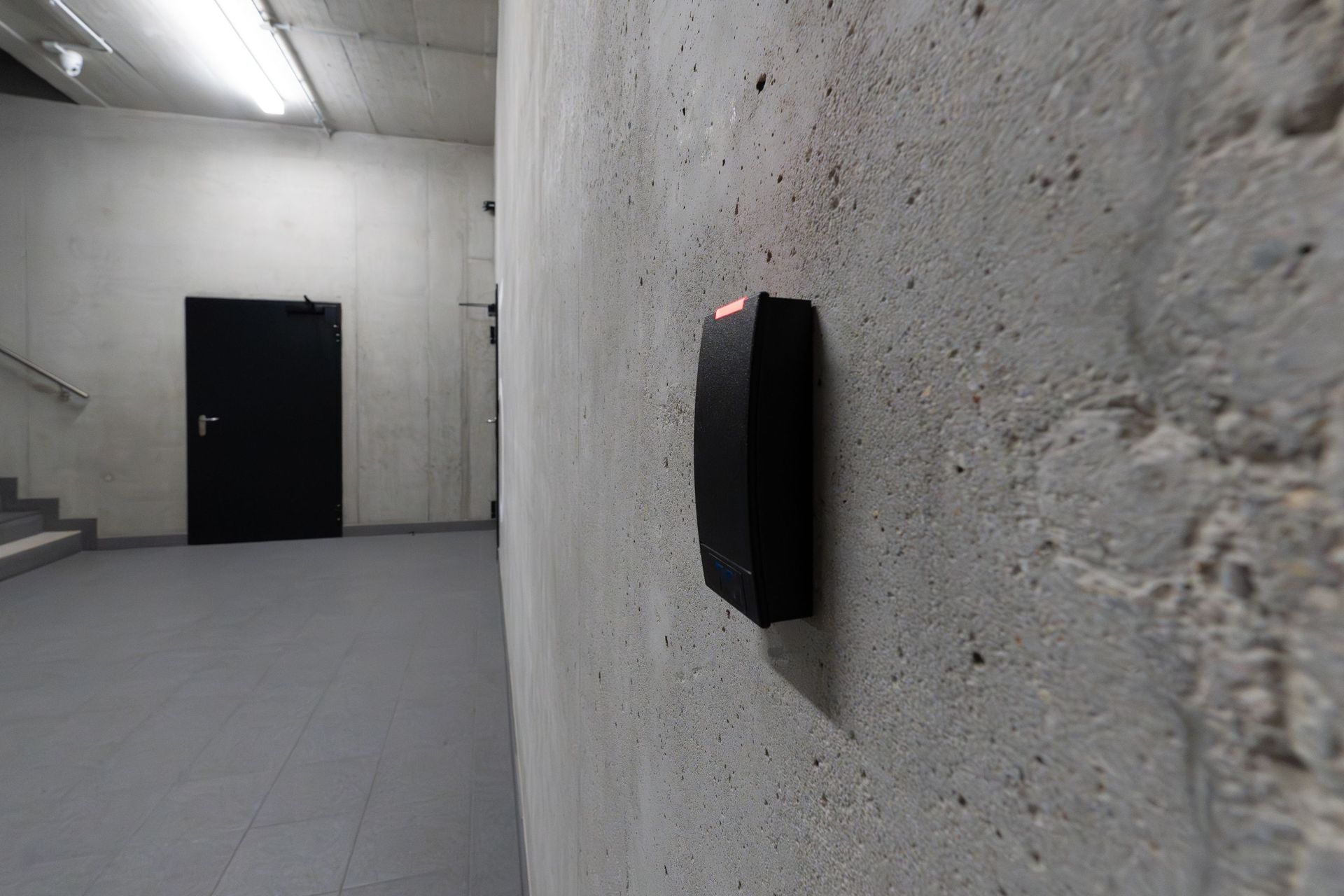 A smart electronic access terminal mounted on a concrete wall in an industrial interior for enhanced security.