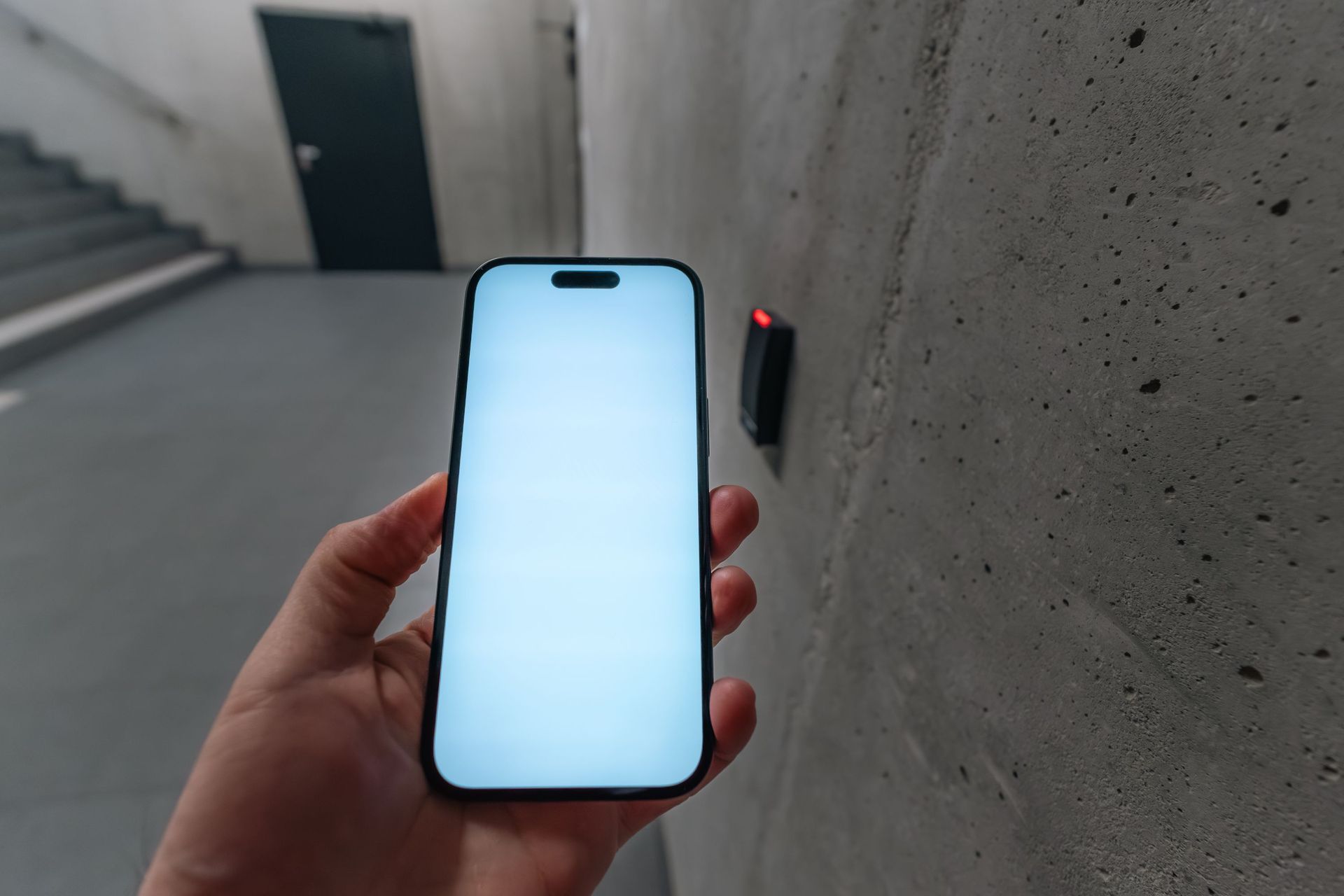 A smartphone unlocking a secure door using NFC technology in a modern building stairwell.